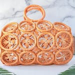 Melon Sprinkles Havana Macrame' Straw Bag by Shebobo Against a Marble and Clean White Background with Palm Leaves